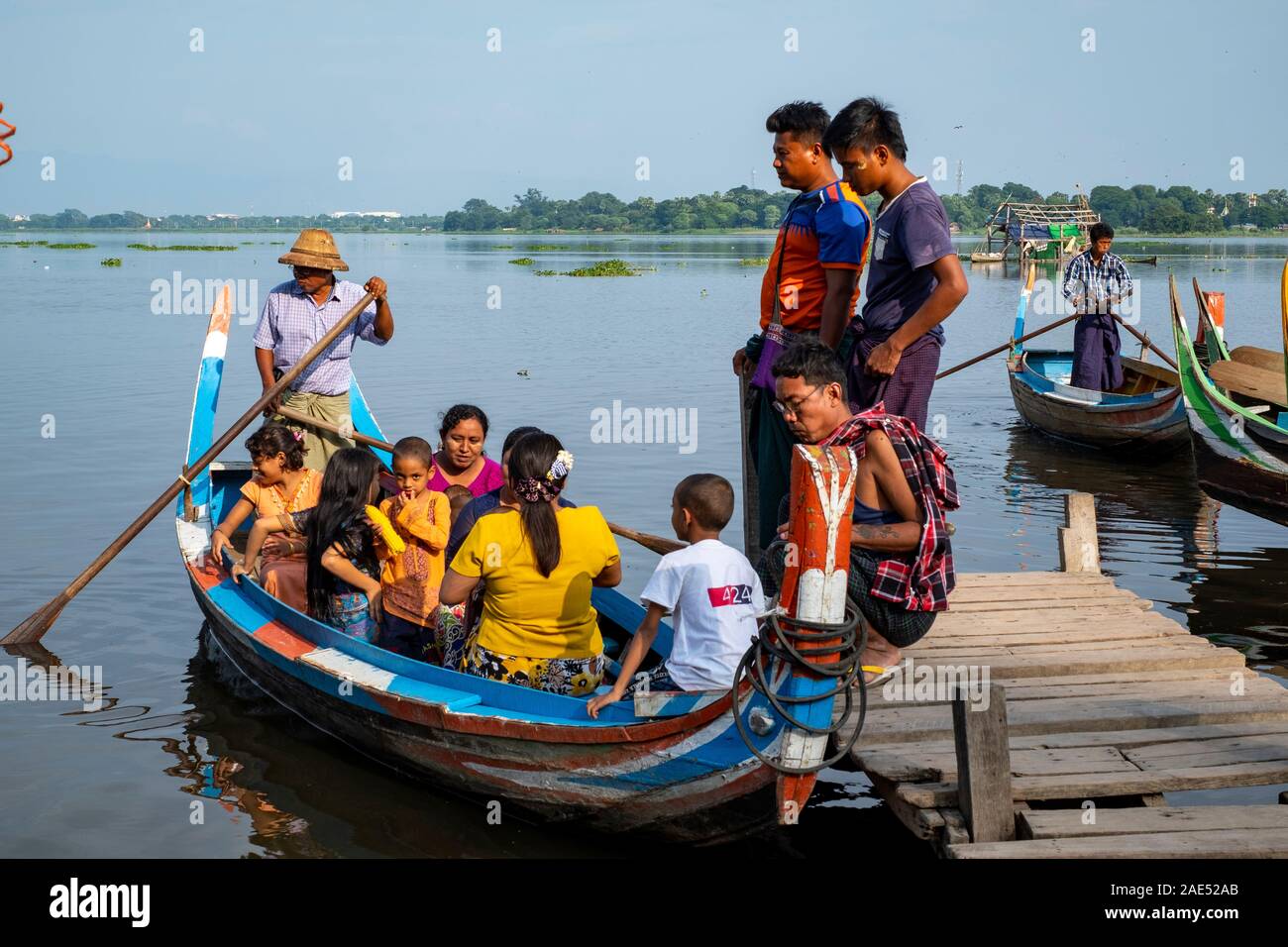 A large family climbs into a traditional Burmese boat to celebrate a local holiday on Lake Thaungthaman near Mandalay, Myanmar (Burma) Stock Photo