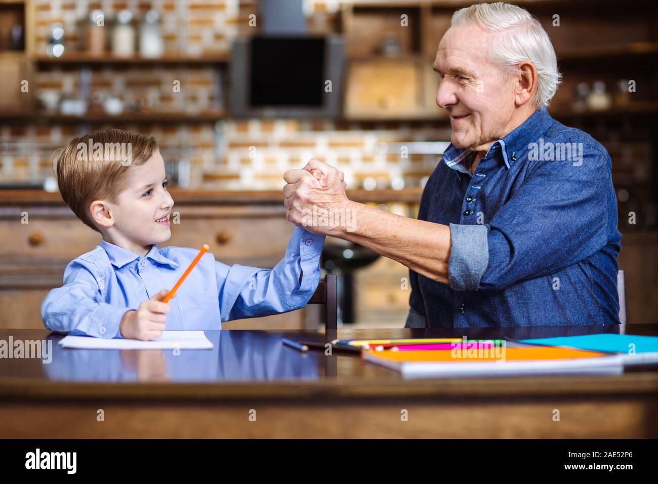 Cheerful little boy and his grandfather shaking hands Stock Photo