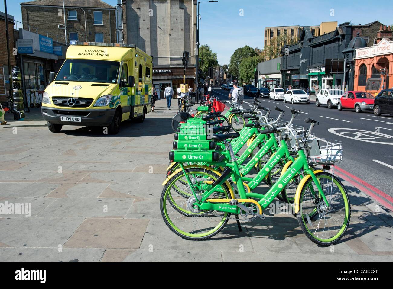 Lime E electric bikes on pavement with ambulance behind, Holloway Road at Highbury Corner, London Borough of Islington Stock Photo