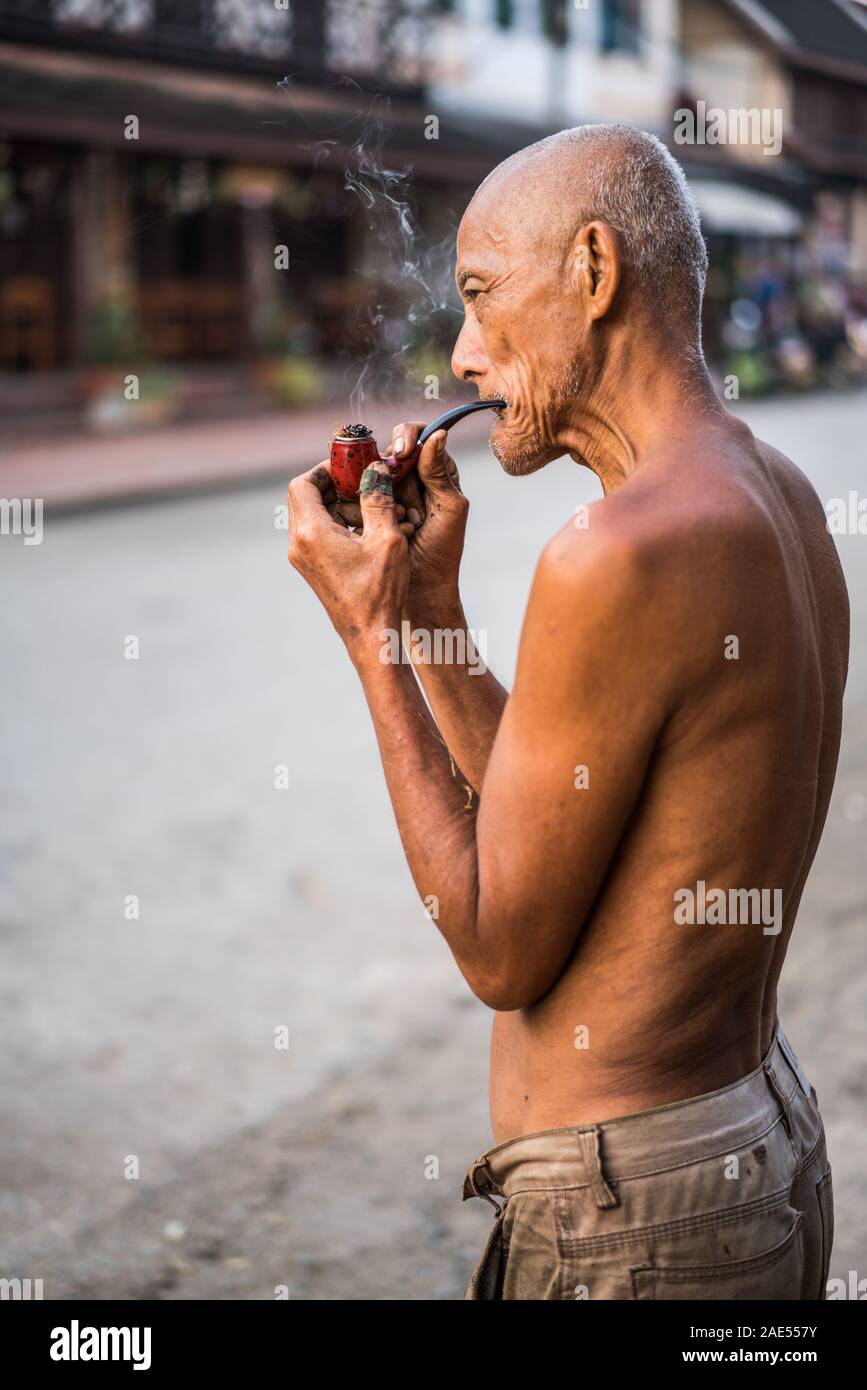 old man smoking pipe in the street of the Luang Prabang, Laos, Asia ...