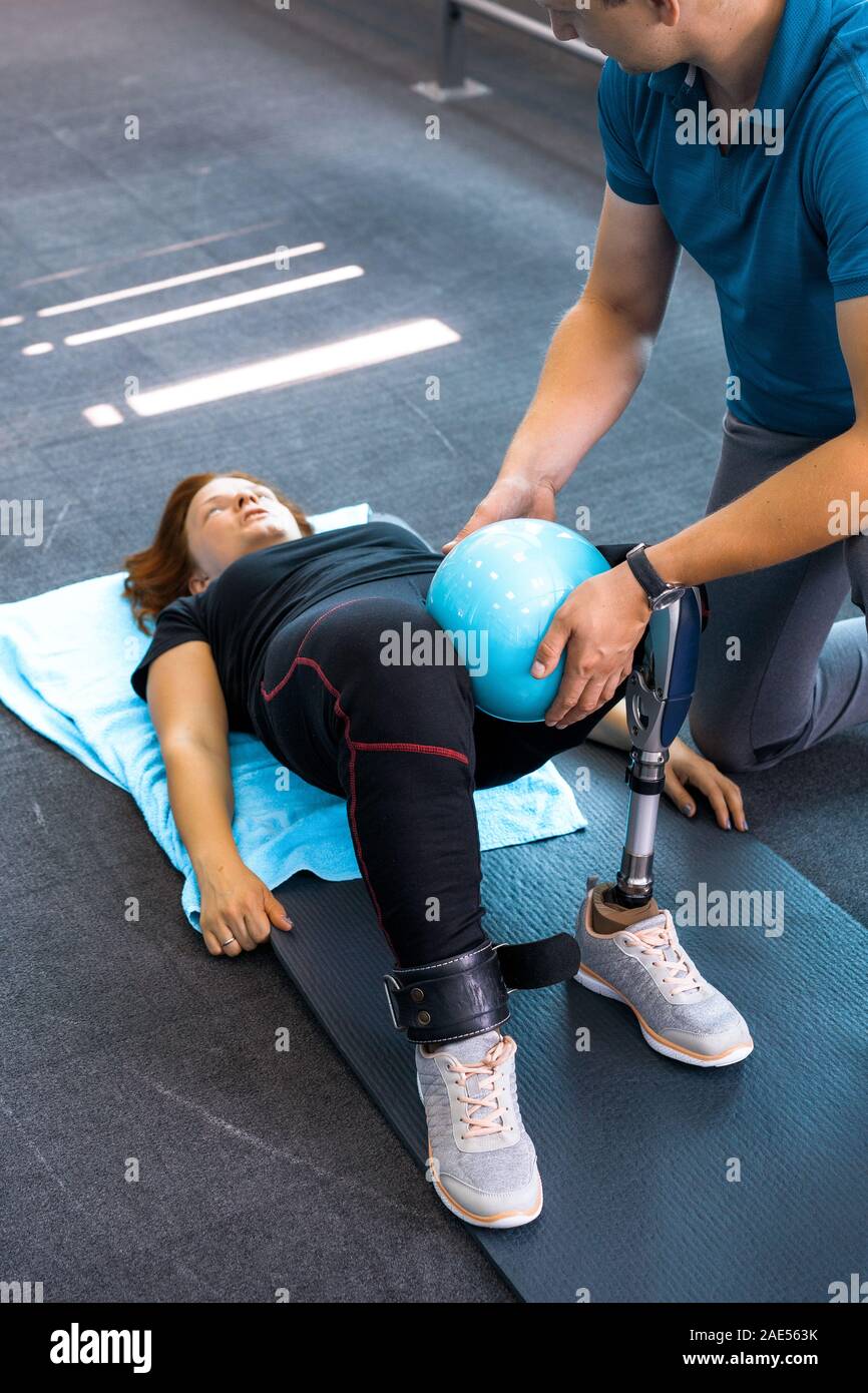 Personal trainer assisting woman with disabilities in her workout ...