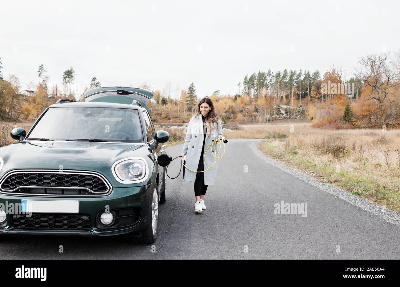 woman walking to plug her electric car into a socket in the country Stock Photo