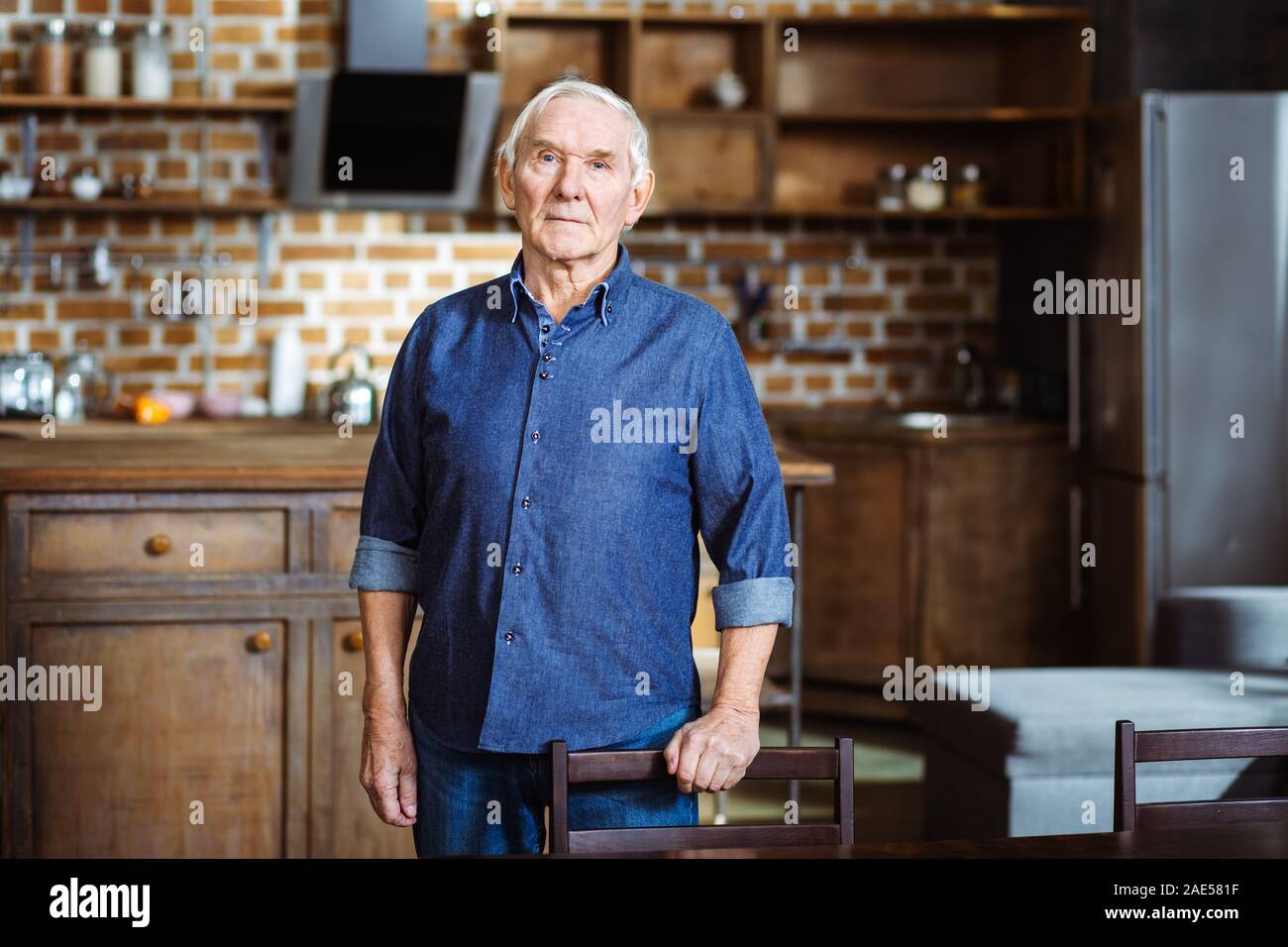 Serious aged man leaning on the chair Stock Photo