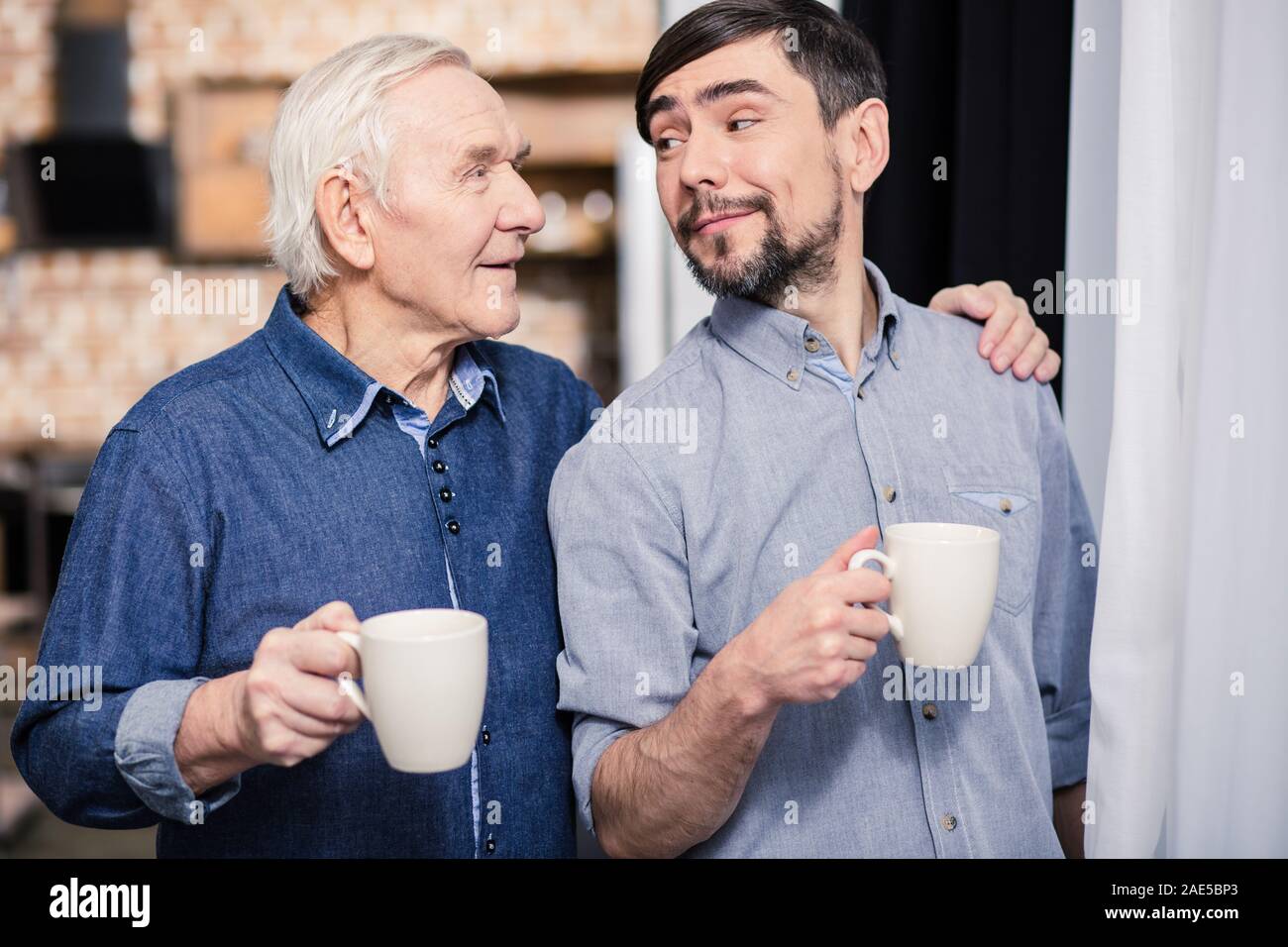 Positive aged man drinking tea with his son Stock Photo