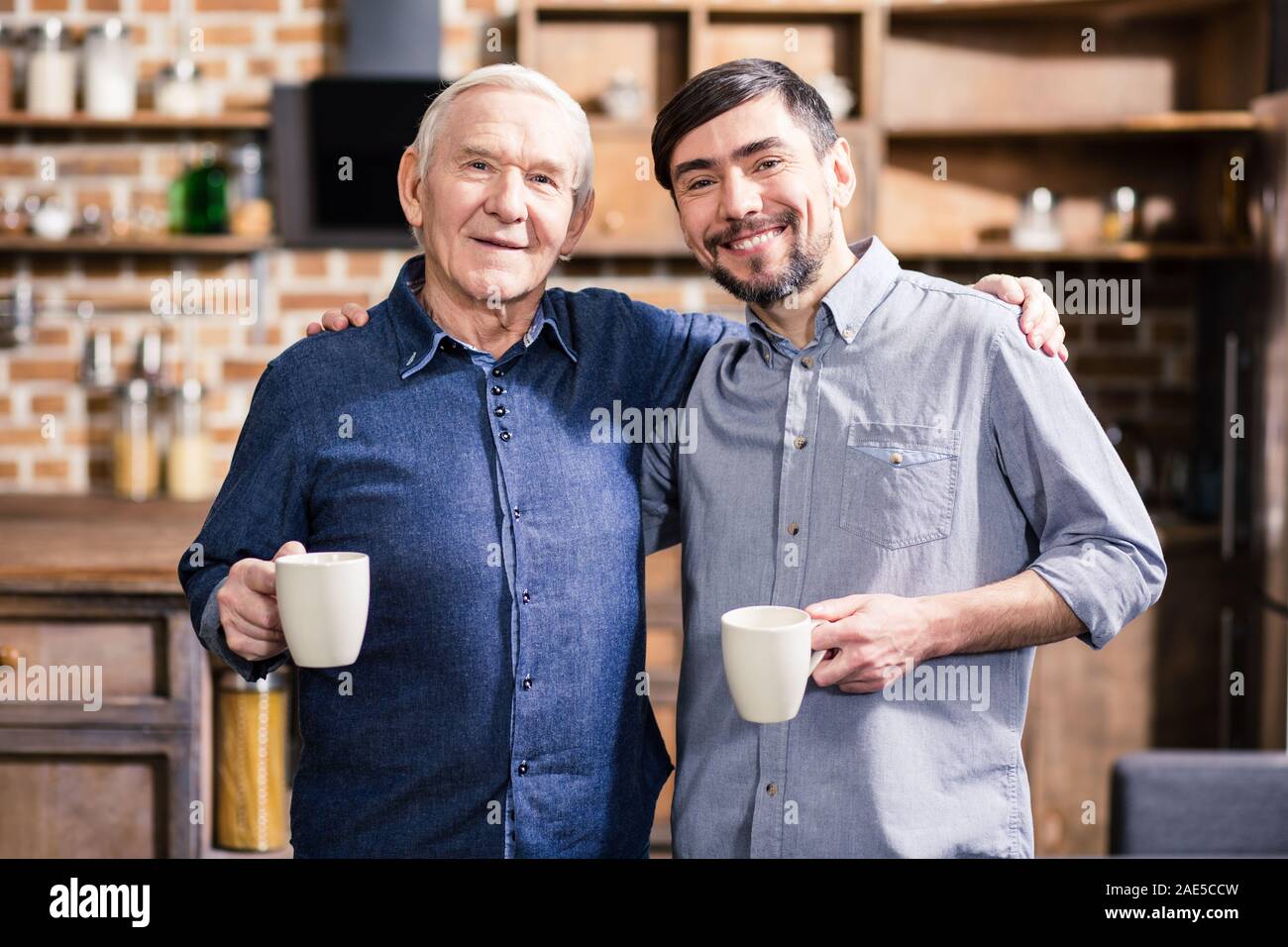 Waist up of cheerful man and his son drinking coffee Stock Photo