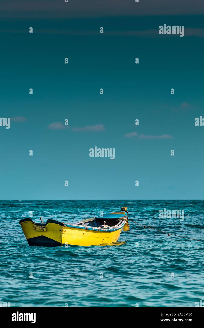 dramatic image of a small yellow fishing boat off the shore in the ...