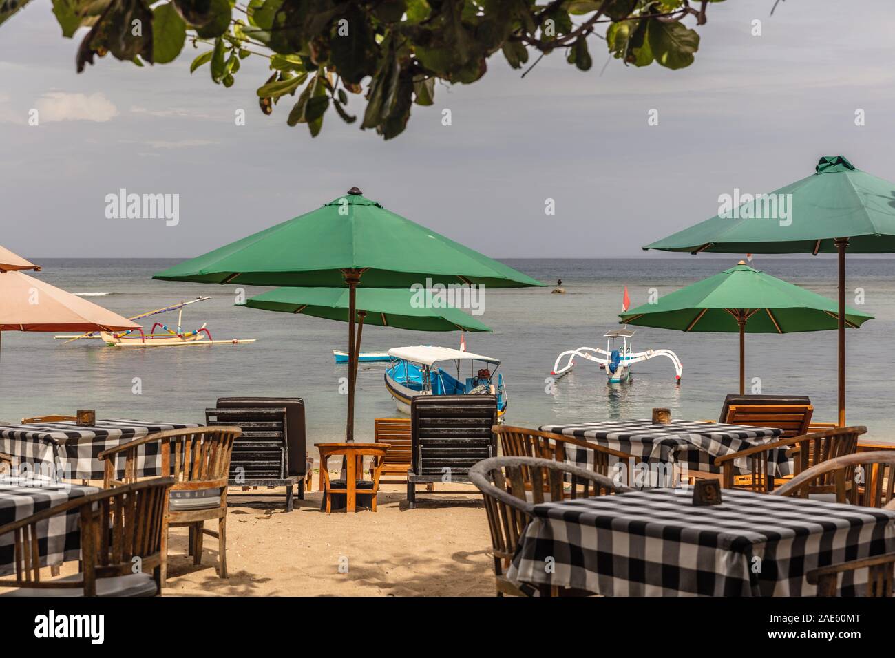 Umbrellas and tables at a beach side cafe at Pantai Sanur, Bali, Indonesia. Stock Photo