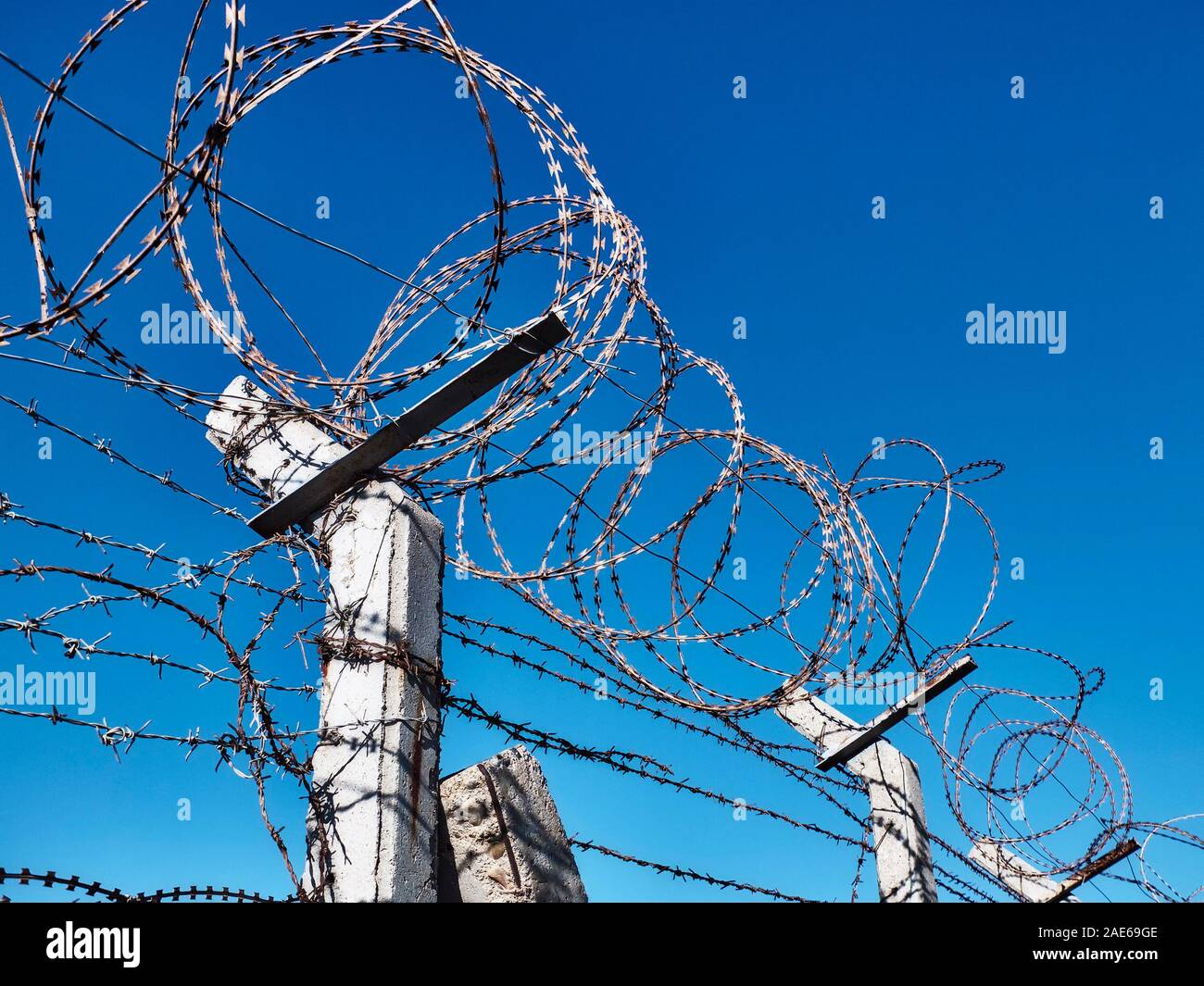 Barbed wire on fence opposite clear blue sky Stock Photo - Alamy