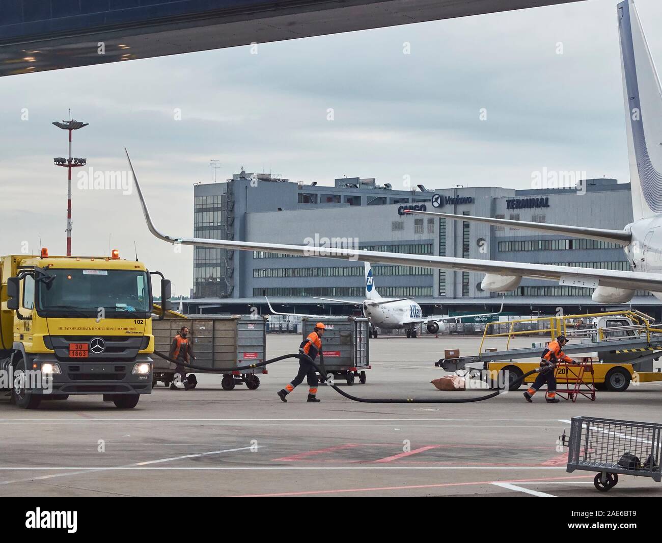 Airport employees are refueling the aircraft with fuel from yellow fuel ...