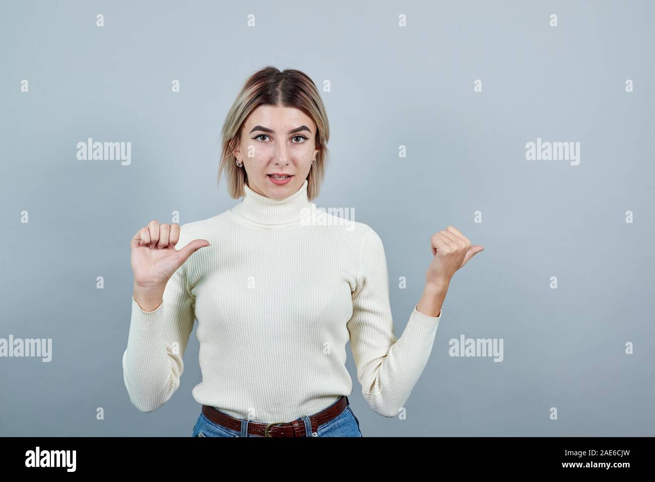 Attractive woman pointing to the side, keeping thumb up, smiling Stock ...