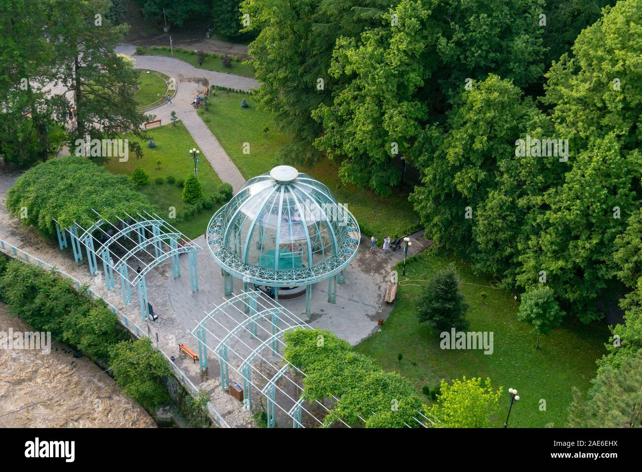 BORJOMI, GEORGIA - JUNE 27, 2019: The Borjomi cable car rides over the Mineral Water Park with its blue pavilion, hiding the water source, Georgia. Stock Photo