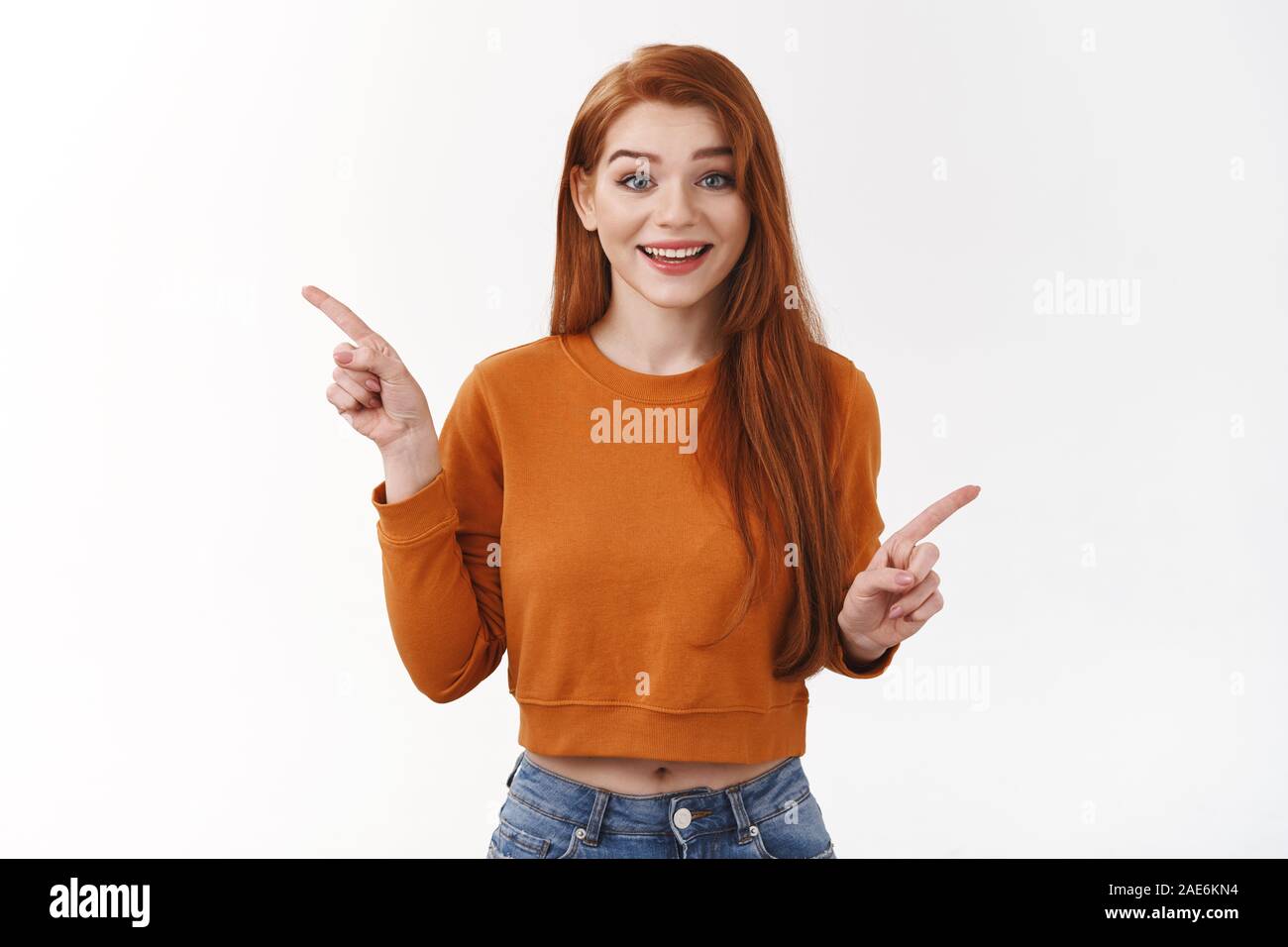 Cheerful smiling happy redhead girl asking advice what better choose, pointing sideways indicating left and right varitants, decide or give suggestion Stock Photo