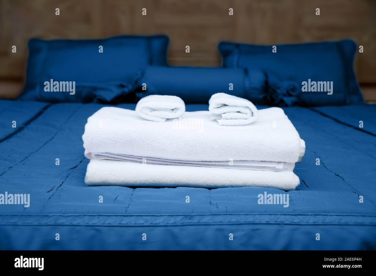 Clean white towels on hotel bed with blue bedding Stock Photo Alamy