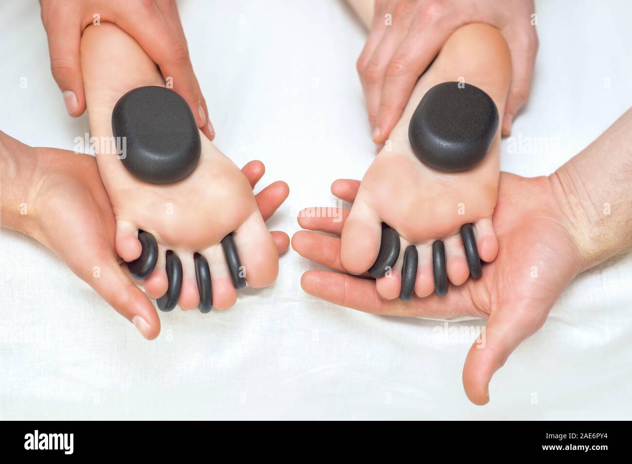 Hot Massage Stones Between The Woman S Toes On The Feet While Massage Therapists Holding Her Feet Stock Photo Alamy