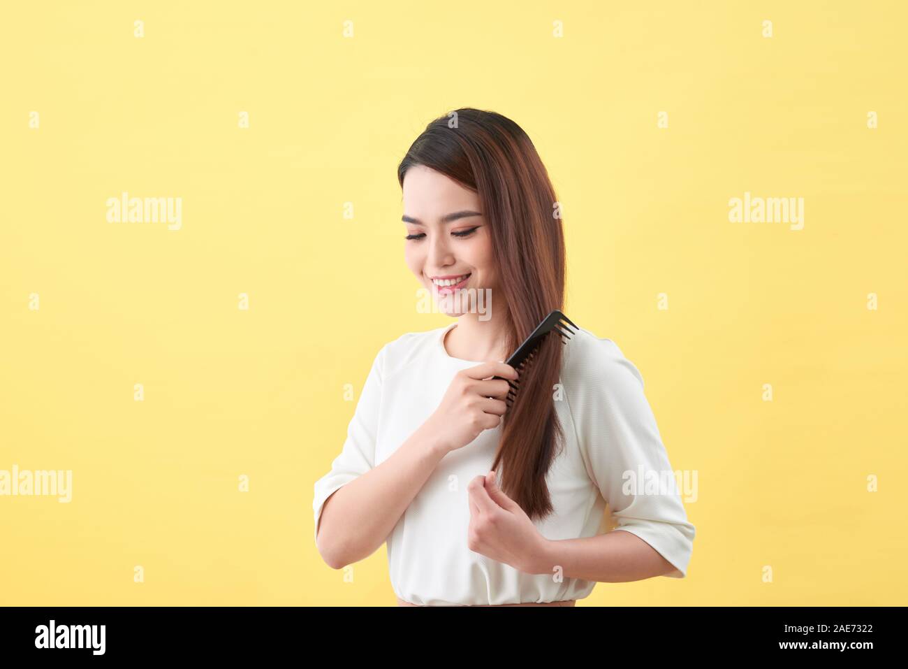 Happy woman brushing her beautiful healthy wavy hair Stock Photo