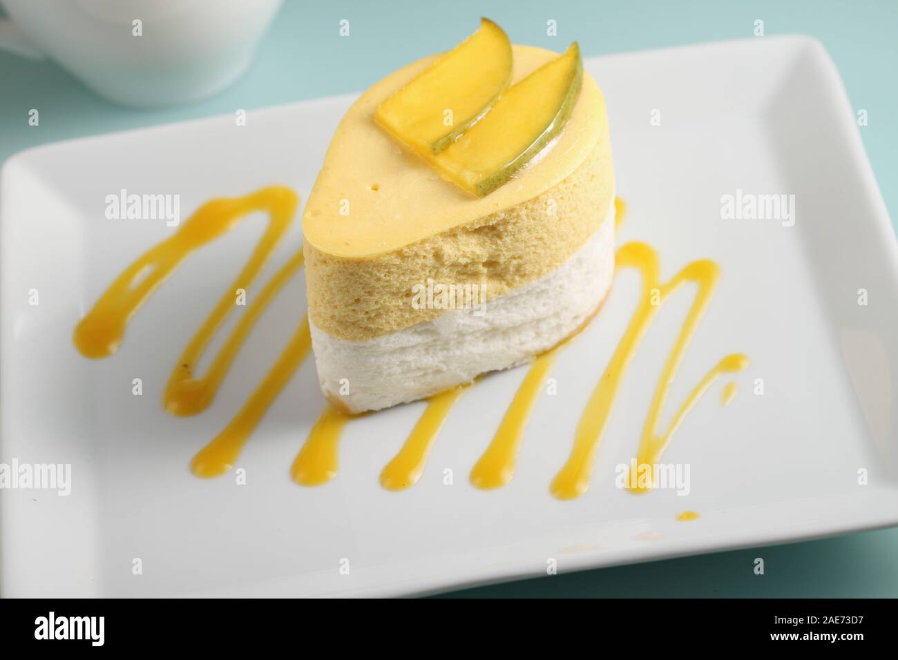 Mango and sour cream dessert topped with slices of mango on a plate decorated with mango puree Stock Photo