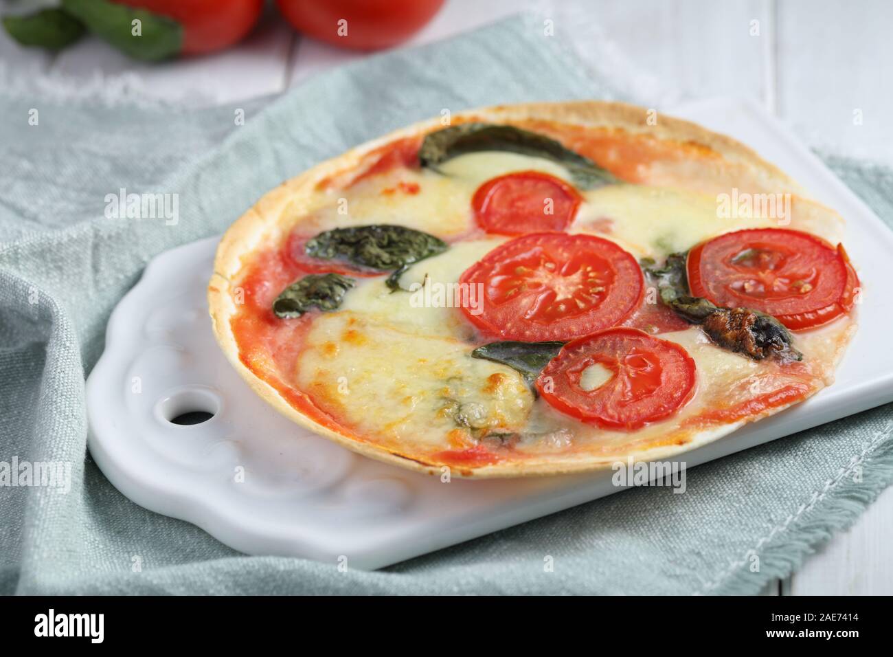 Tortilla pizza Margherita with mozzarella, tomato, and basil on a rustic table Stock Photo