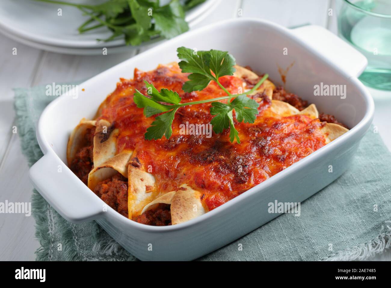 Three enchiladas decorated with parsley in a baking dish closeup Stock Photo