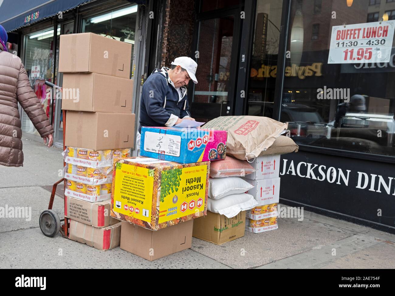 A delivery man, likely Hispanic, delivers food to the Jackson Diner Indian restaurant on 74th Street in Jackson Heights, Queens, New York City. Stock Photo