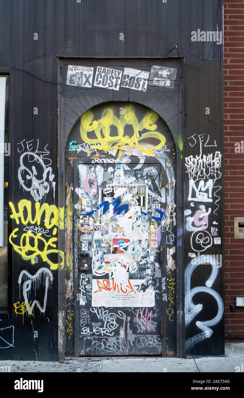 A Manhattan doorway collage on Eighth Ave. just below 14th Street with graffiti, stickers and tagging. In New York City. Stock Photo