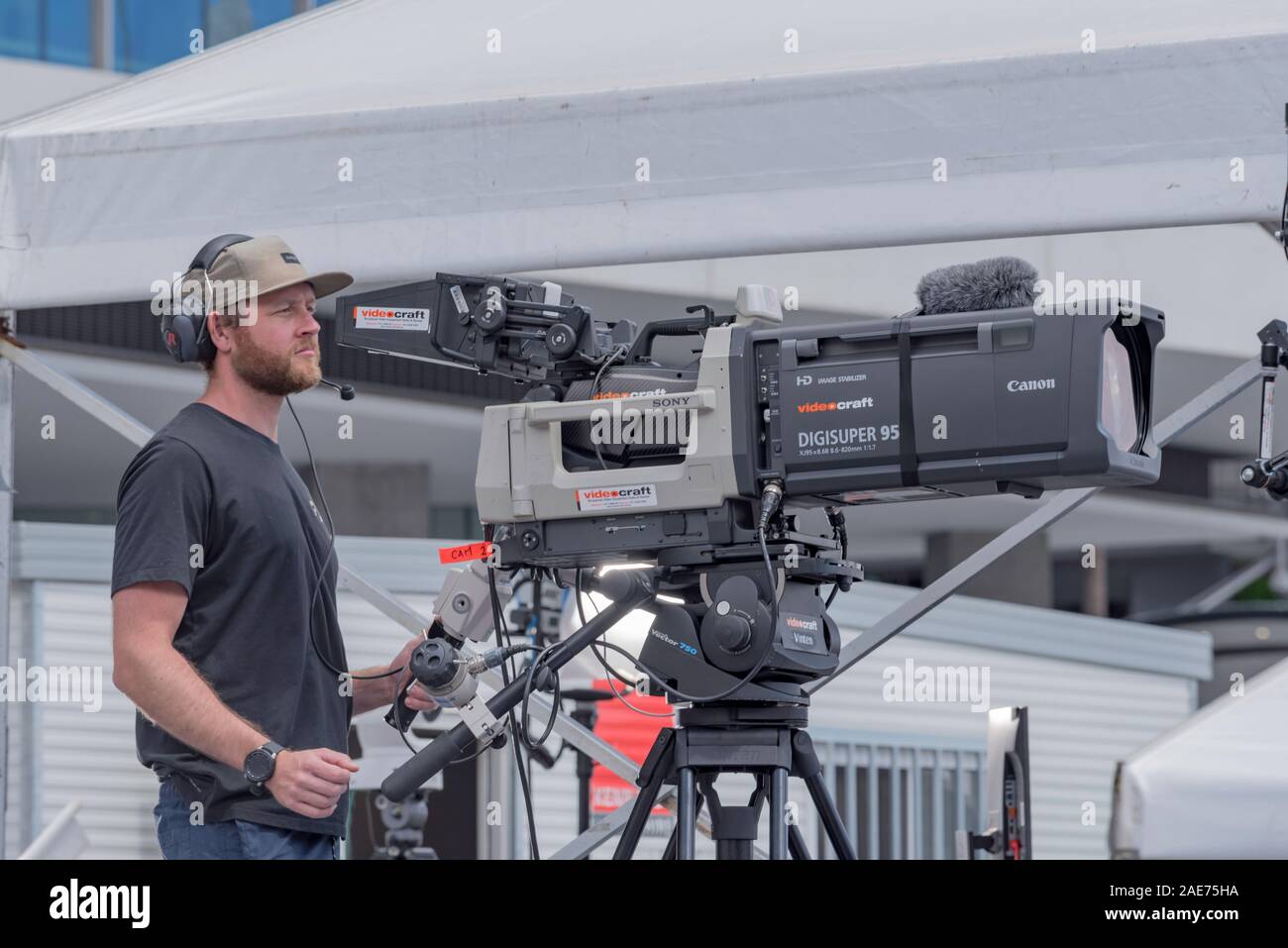 A white male man in his mid thirties operating an outside broadcast television camera on a sunny day in Sydney Australia Stock Photo