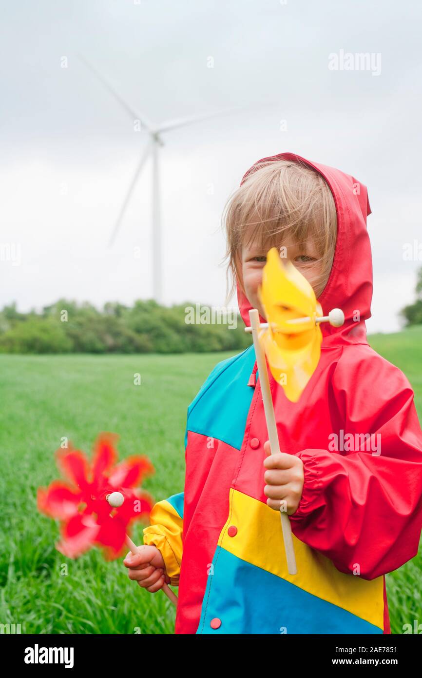 Boy with two pinwheels in front of wind farm. Stock Photo