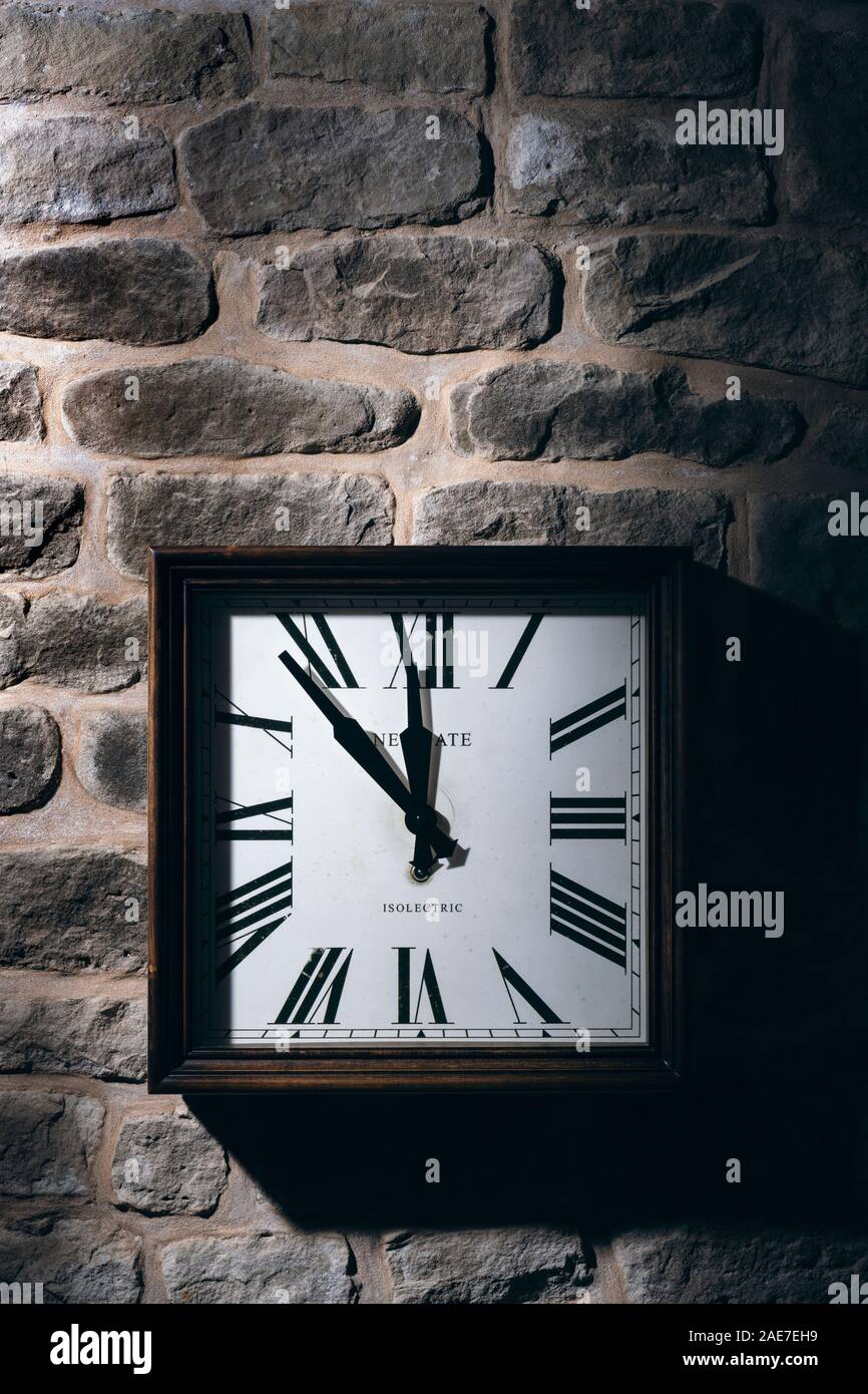 Square clock hanging on a stone wall. Stock Photo