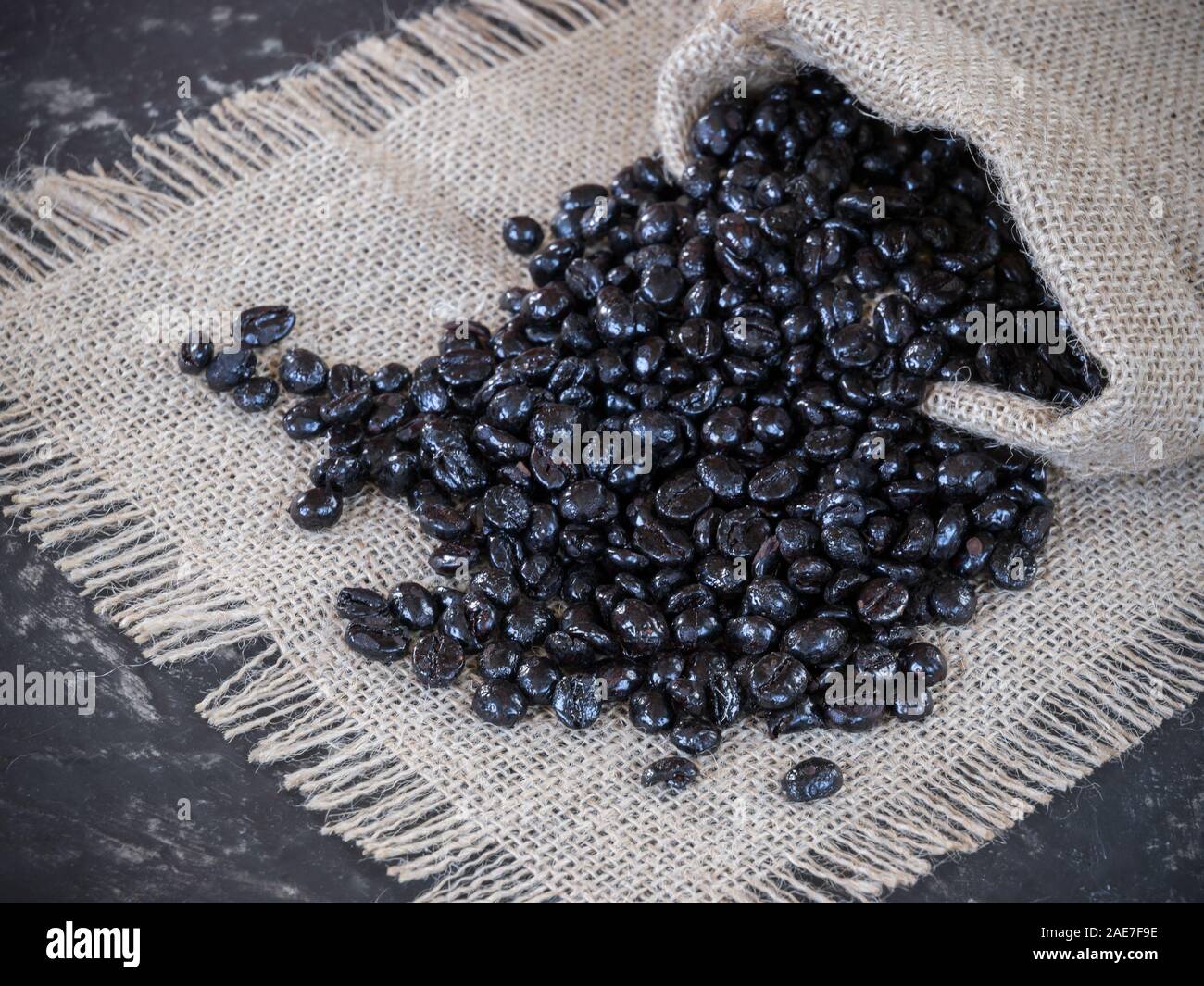 Beans Beg bag with coffee beans coming out of the bag on the stone table Stock ...