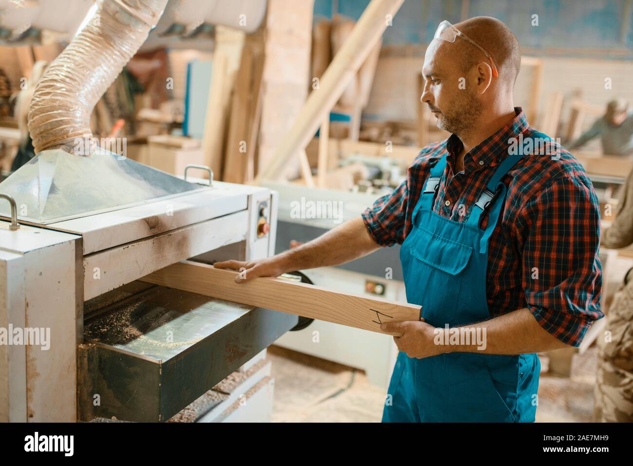 Carpenter works on plane machine, woodworking Stock Photo