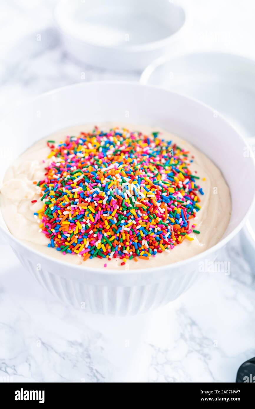 Mixing ingredients to bake birthday funfetti cake with colorful