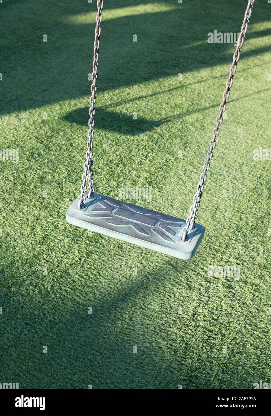 Empty swing on children playground,Children swing in the park,wooden swing,wooden swing with artificial grass Stock Photo