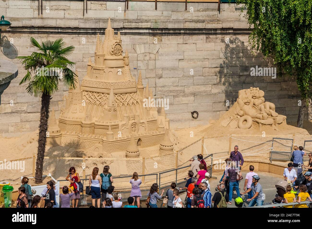 People admiring the huge sand sculpture of a castle with Mickey Mouse and Minnie Mouse at Quai du Louvre during the popular Paris Plage days on a nice... Stock Photo