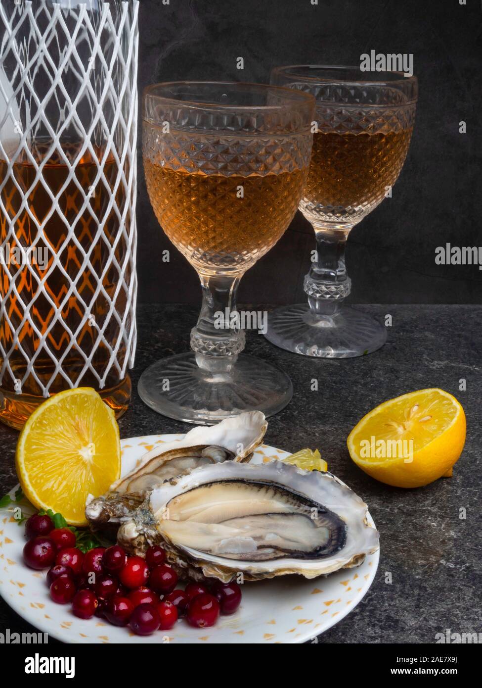 Fresh oysters in ice with wine or champagne bottle, lemon, cranberries. Food background Stock
