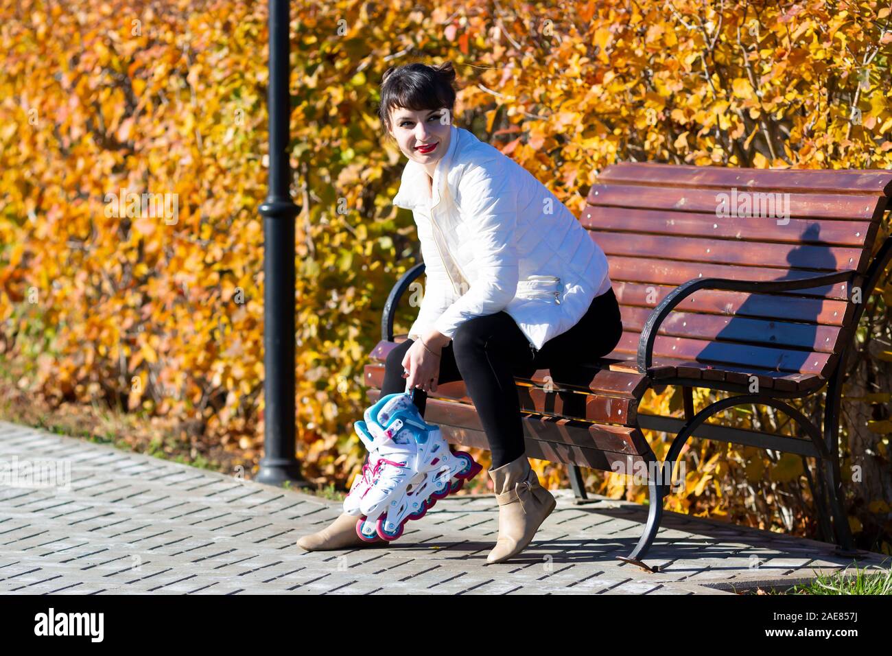 A Young Woman In A White Jacket Sits On A Bench Holds Roller