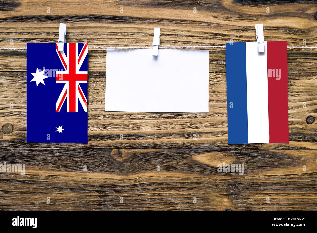 Hanging flags of Heard and Mcdonald Islands and Netherlands attached to rope with clothes pins with copy space on white note paper on wooden backgroun Stock Photo