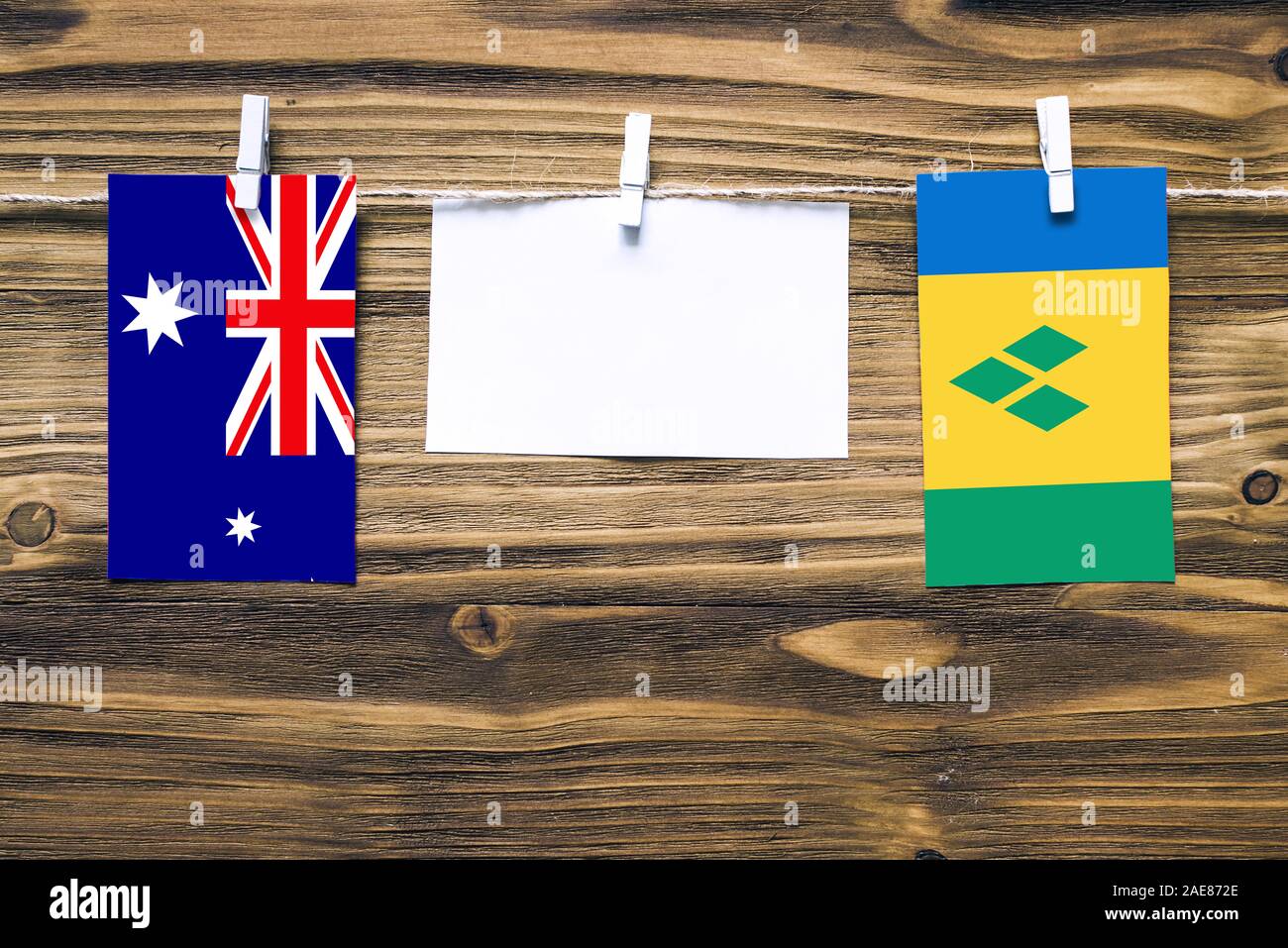 Hanging flags of Heard and Mcdonald Islands and Saint Vincent And The Grenadines attached to rope with clothes pins with copy space on white note pape Stock Photo