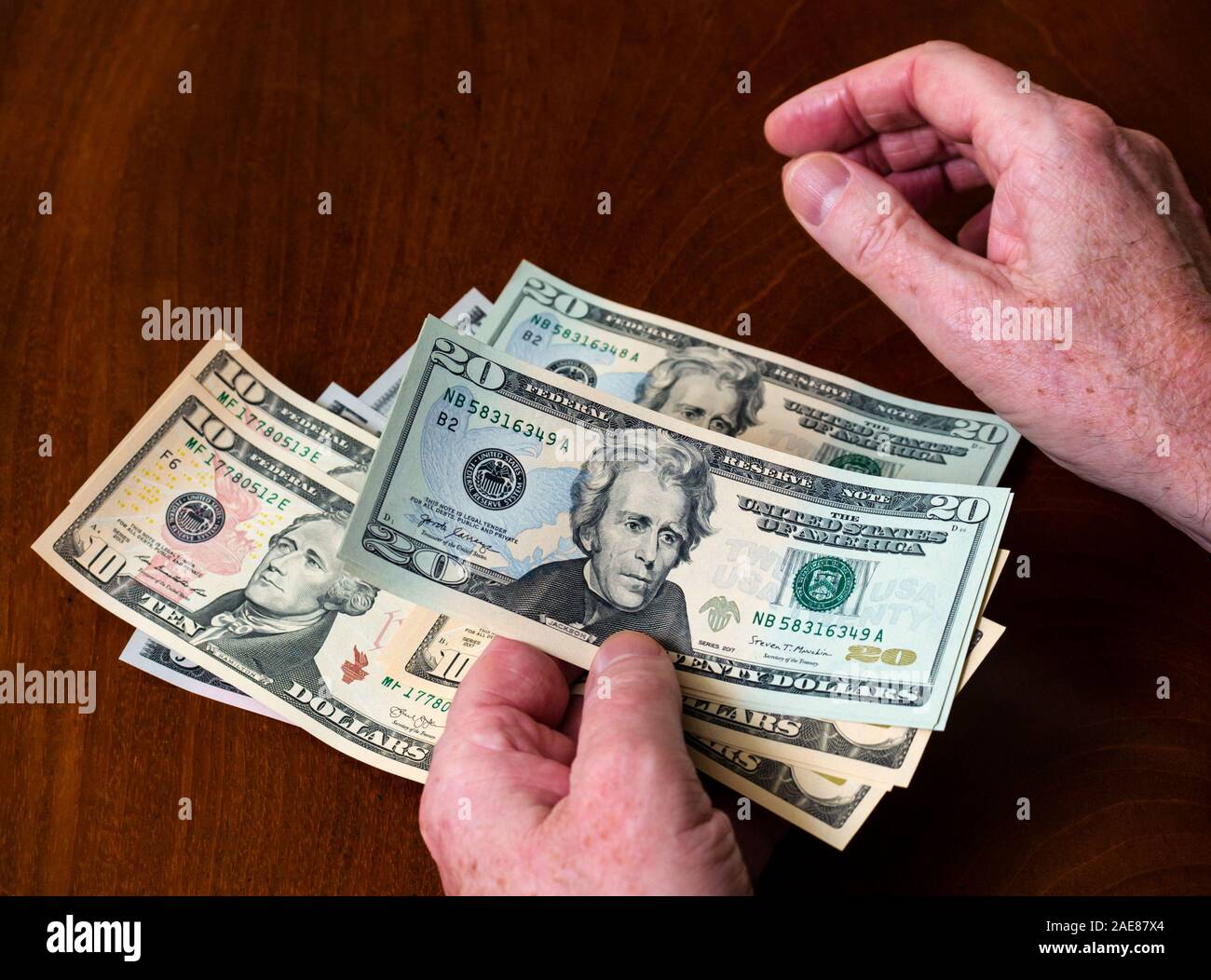 Man counting American (US) money with five, ten & twenty dollar bills features US president Andrew Jackson Stock Photo