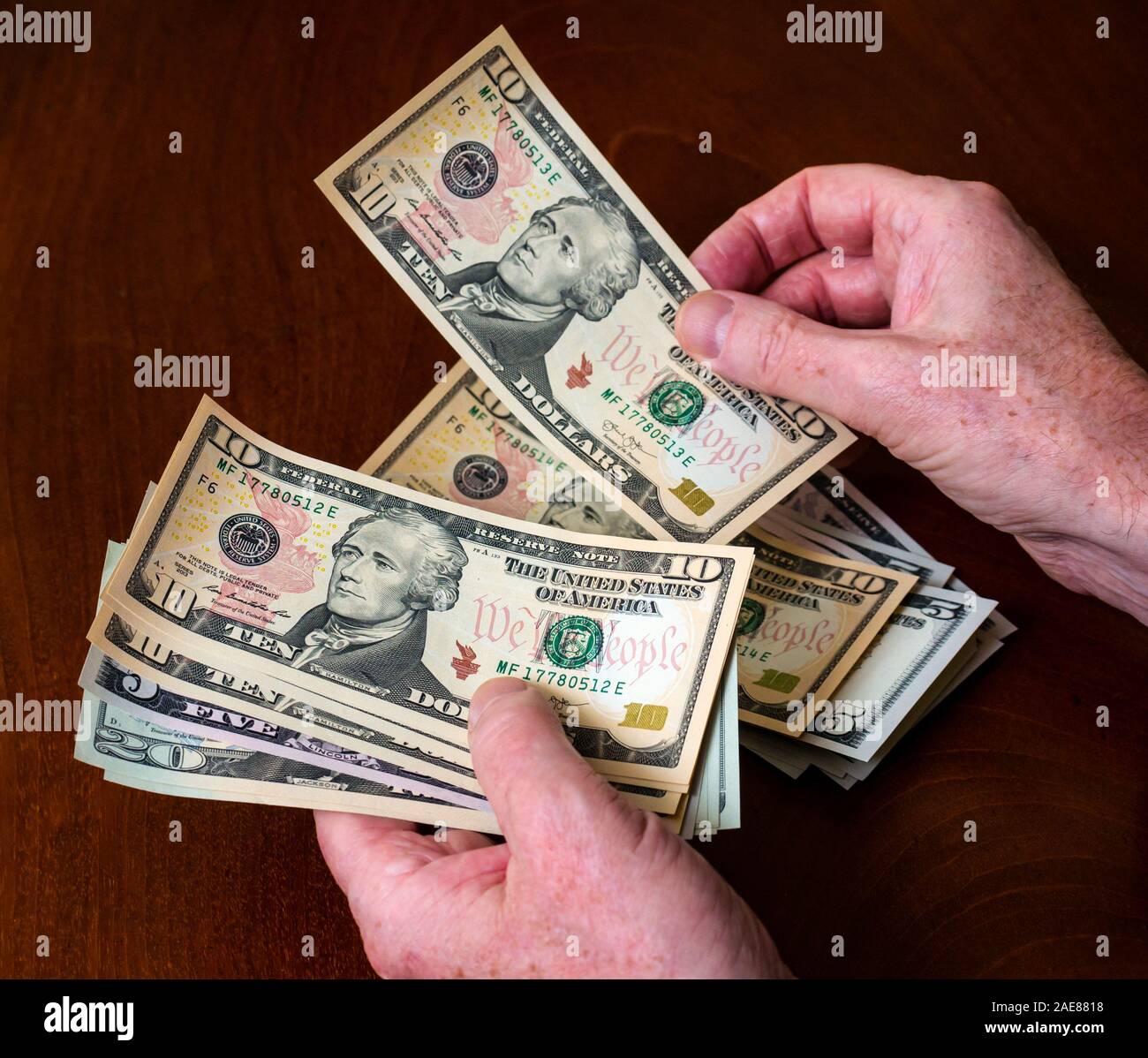 Man's hands counting American (US) money with five, ten & twenty dollar bills with US president Alexander Hamilton Stock Photo