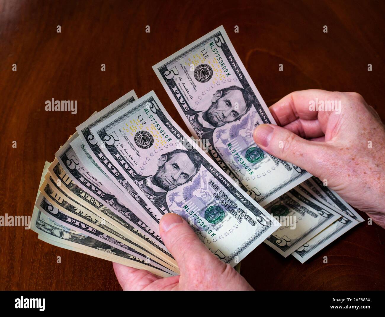 Man hands counting American (US) money with five, ten & twenty dollar bills with US president Abraham Lincoln Stock Photo