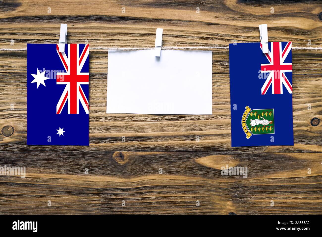 Hanging flags of Heard and Mcdonald Islands and British Virgin Islands attached to rope with clothes pins with copy space on white note paper on woode Stock Photo