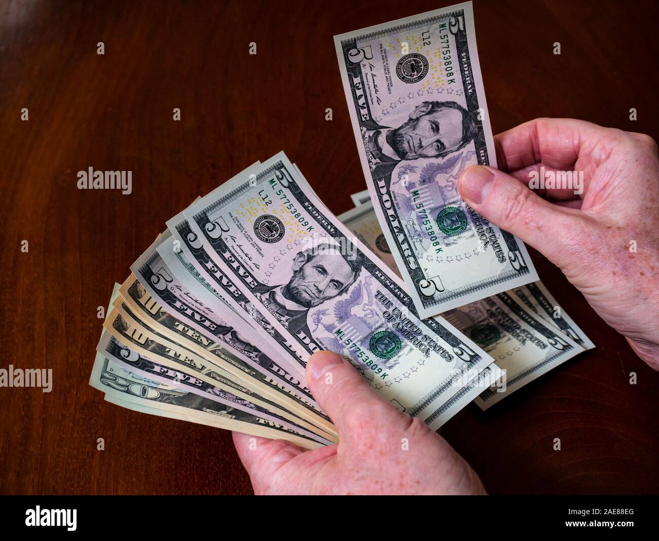 Man  hands counting American (US) money with five, ten & twenty dollar bills with US president Abraham Lincoln Stock Photo