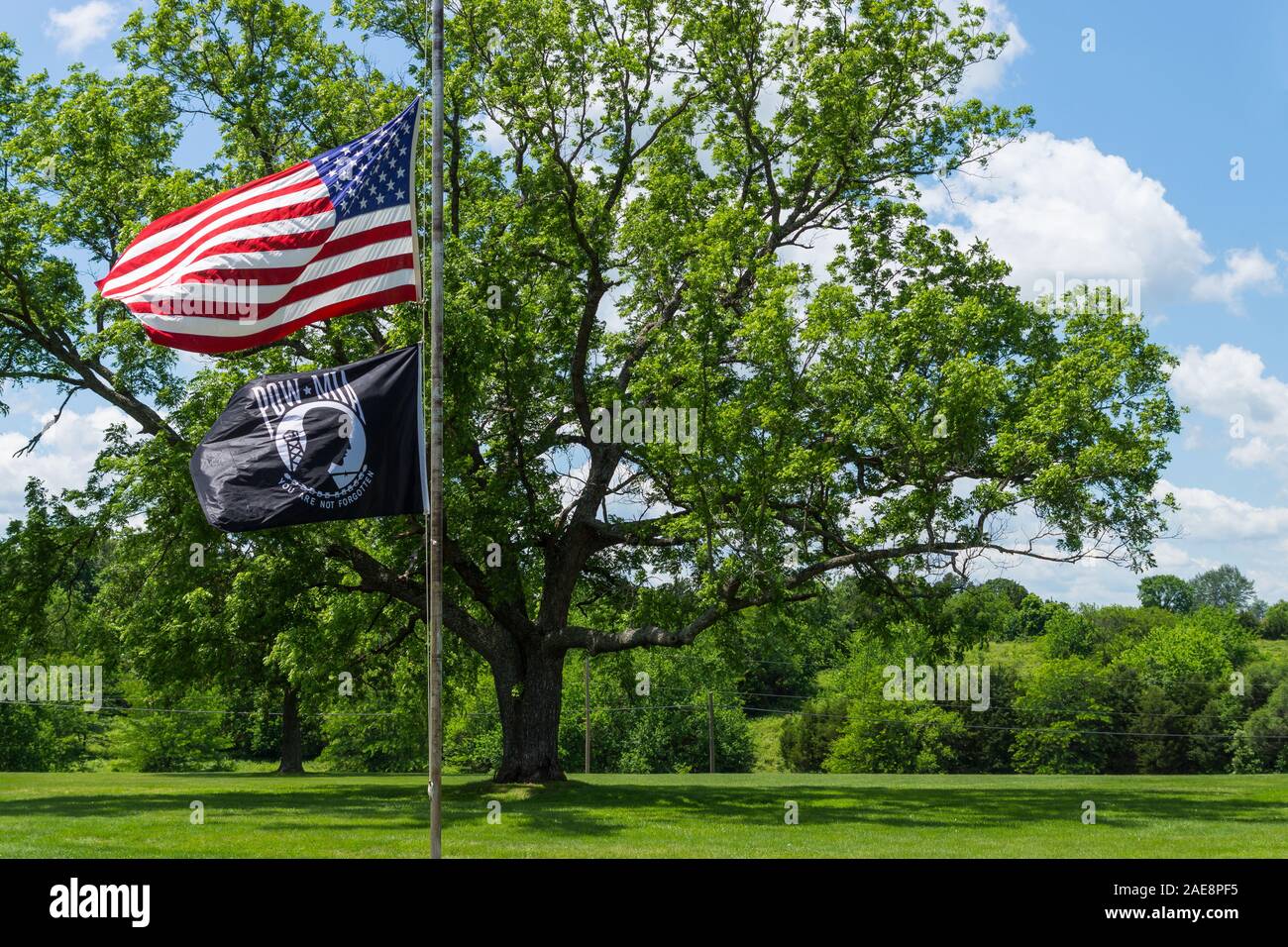 The American Flag and POW / MIA Flag flys in the wind at a cemetary over Memorial weekend in Humansville, Missouri. Stock Photo