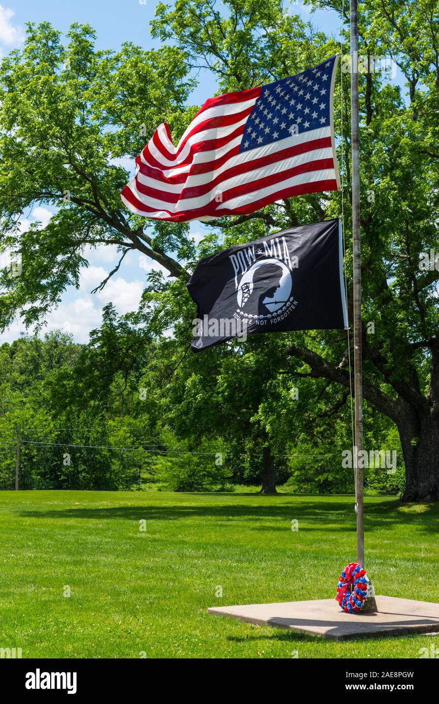 The American Flag and POW / MIA Flag flies in the wind at a cemetery