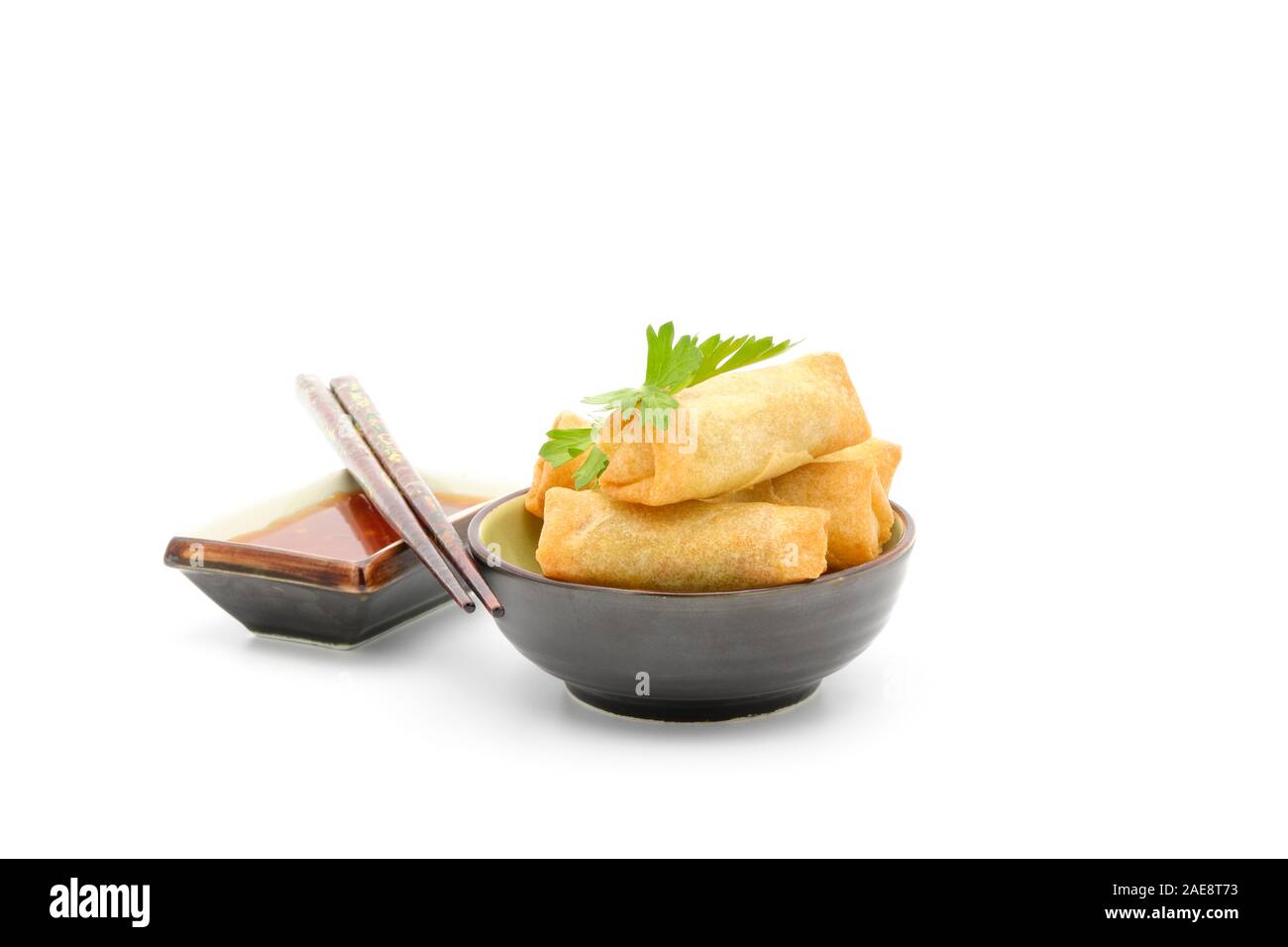 Bowl of vegetarian Thai spring rolls served with a spicy dipping sauce on a white background. Stock Photo