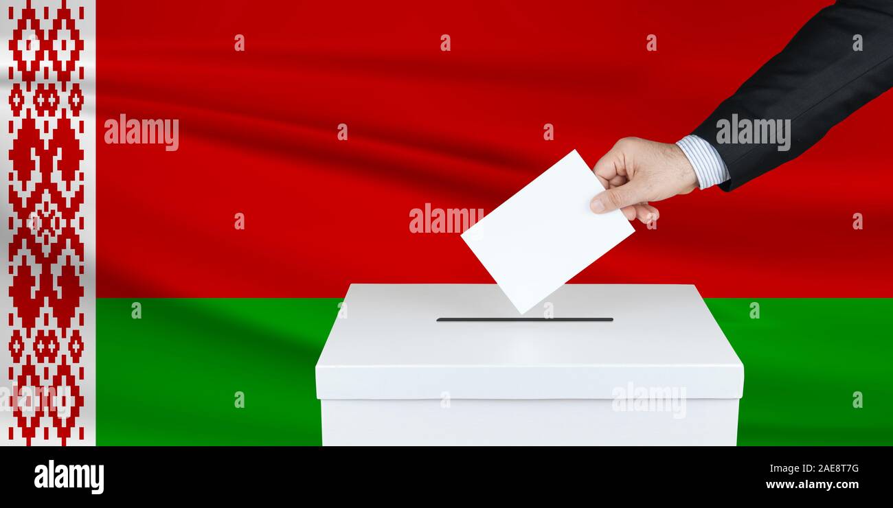 Election in Belarus The hand of man putting his vote in the ballot box. Waved Belarus flag on background. Stock Photo
