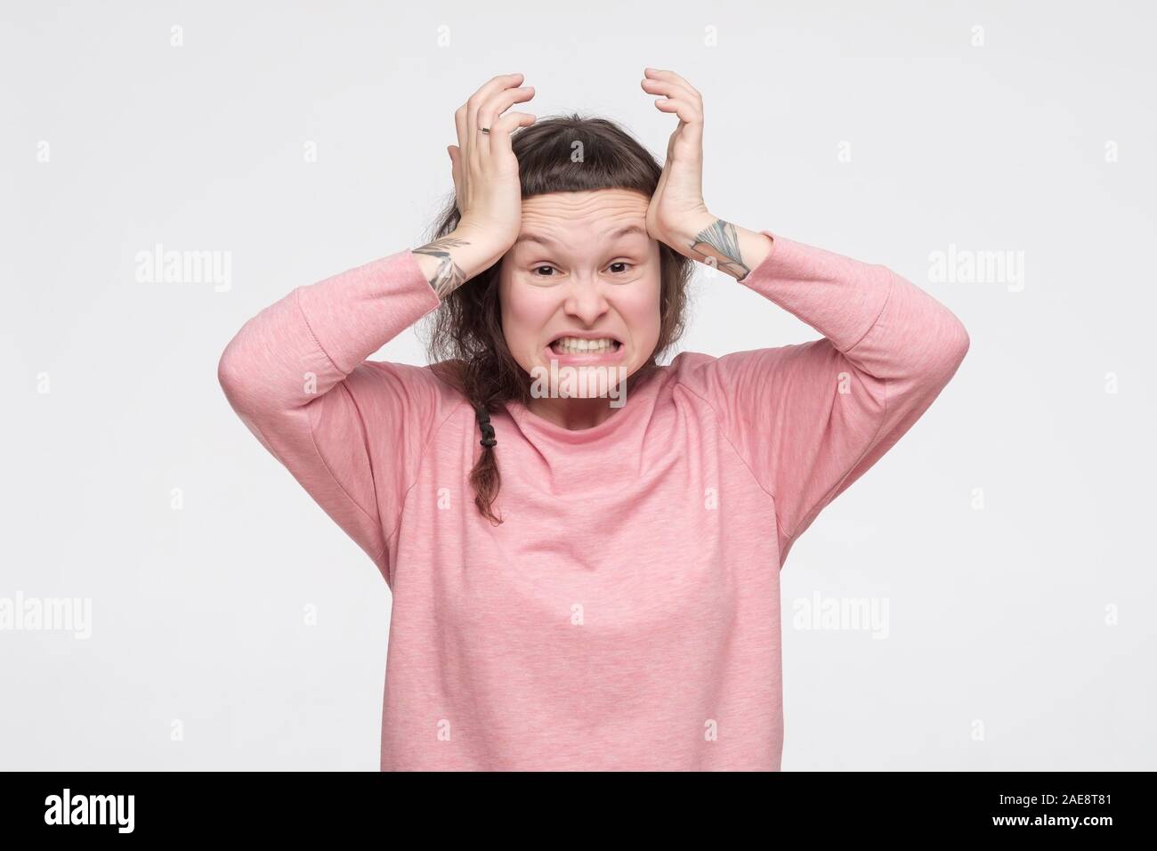 Young angry caucasian woman in pink clothes being irritated and angry with your stupid words. Studio shot Stock Photo