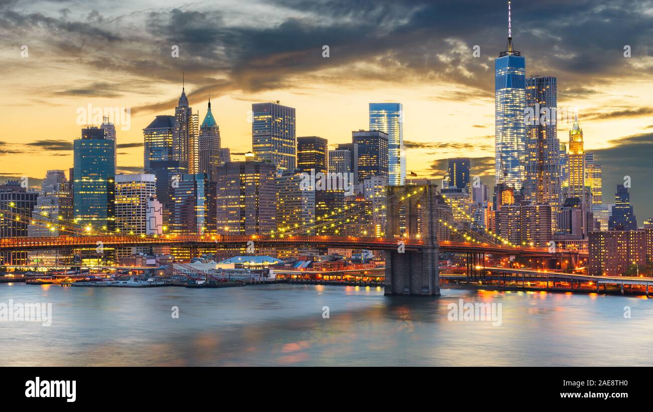 New York, New York, USA downtown Manhattan city skyline over the East River with the Brooklyn Bridge at dusk. Stock Photo
