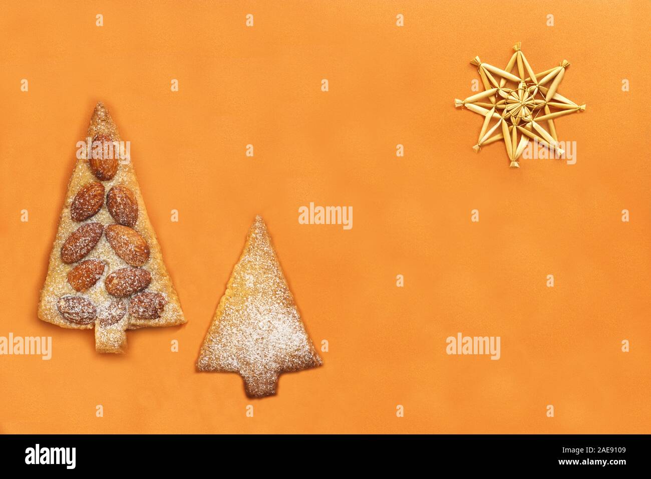 gold colored christmas card with straw star, cookies in coniferous tree shape  and copy space Stock Photo