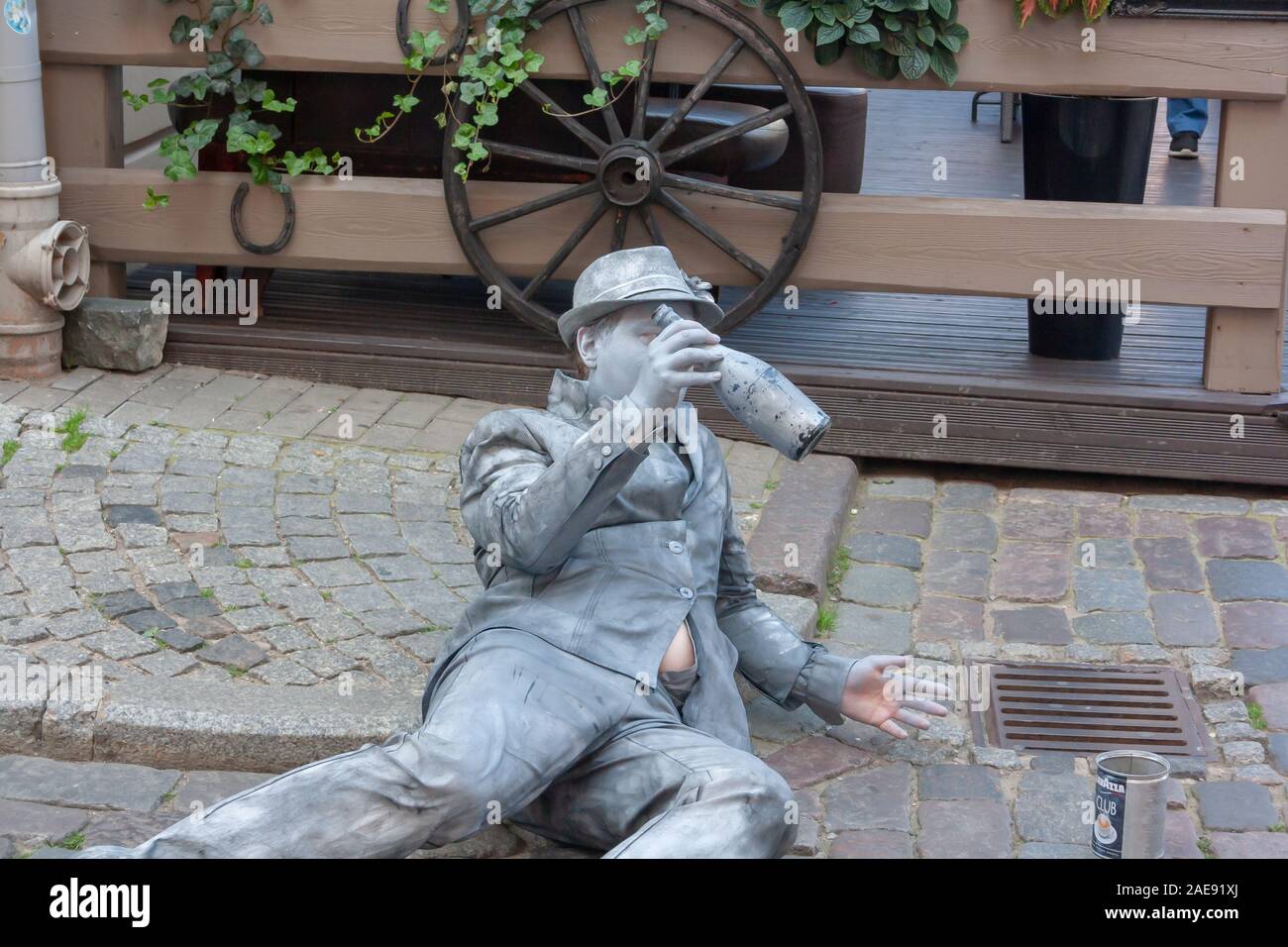 Old Riga, Latvia -18.08.2019. The drinker's mime is lying on the street with a bottle in his hands Stock Photo