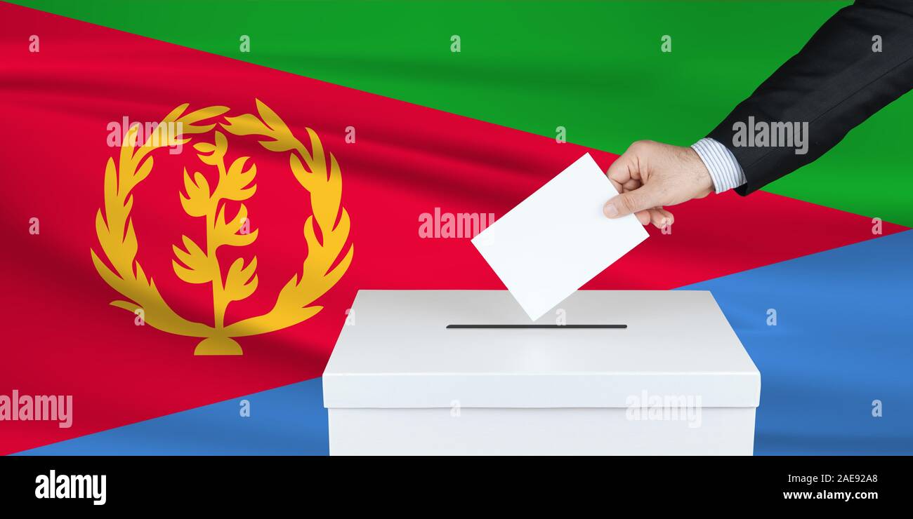 Election in Eritrea. The hand of man putting his vote in the ballot box. Waved Eritrea flag on background. Stock Photo